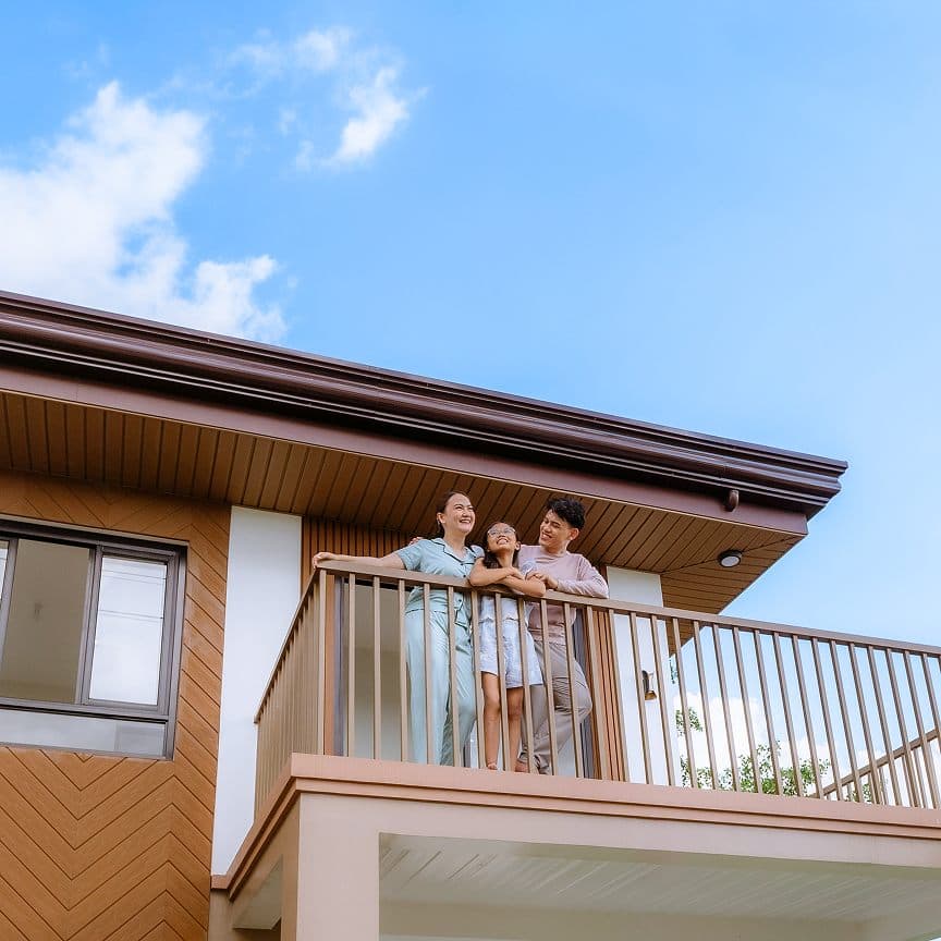 Family standing on the balcony of a Los Rayos home under a clear blue sky
