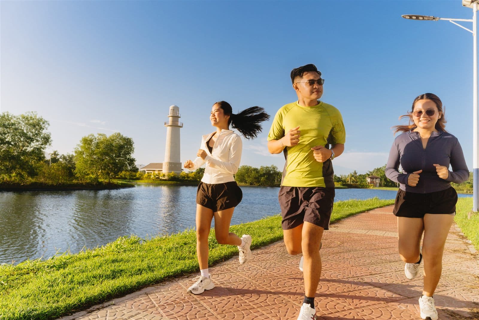 Residents jogging along the Los Rayos lakeside path with the lighthouse in the background