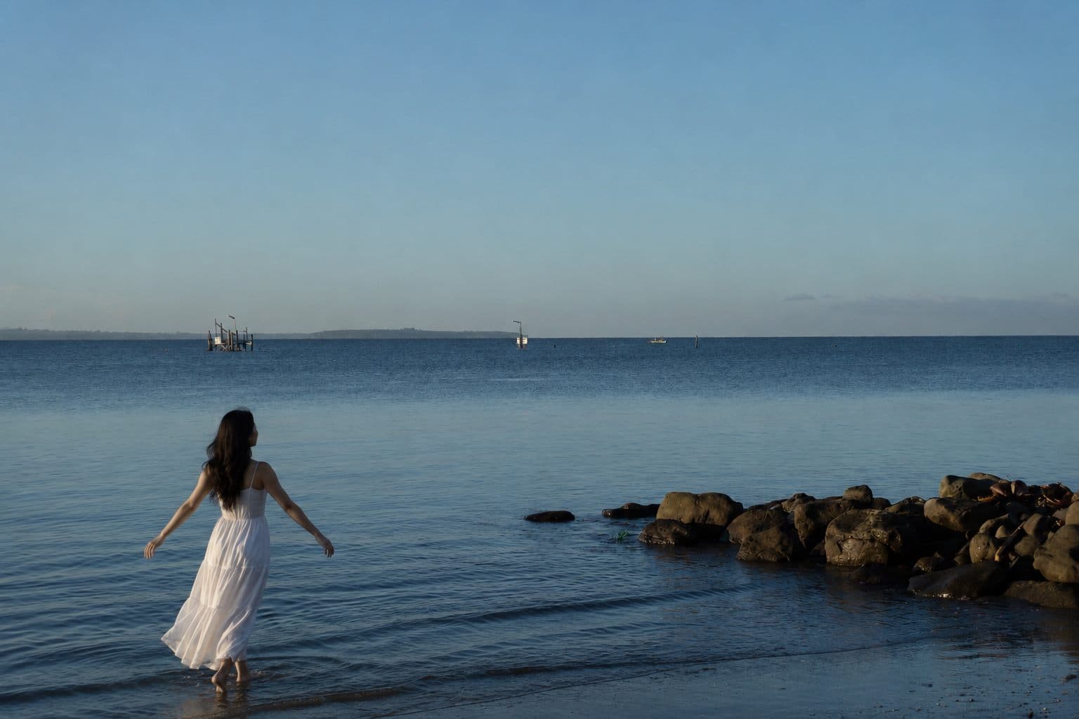 A woman walking along the calm shore of the Davao Gulf